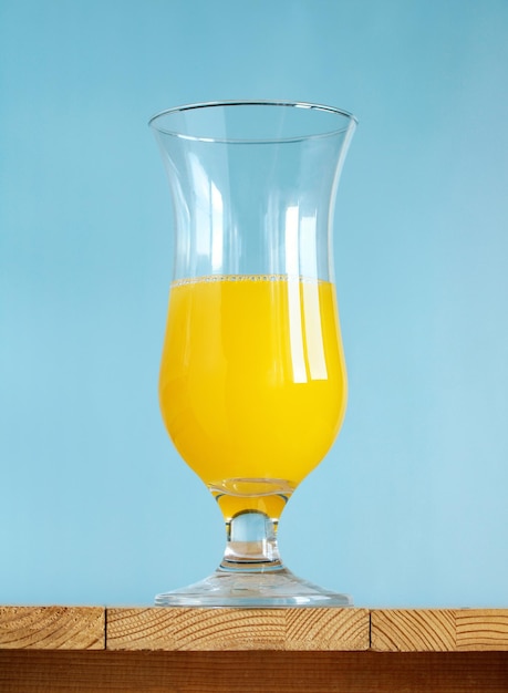 Glass with a yellow drink on a blue