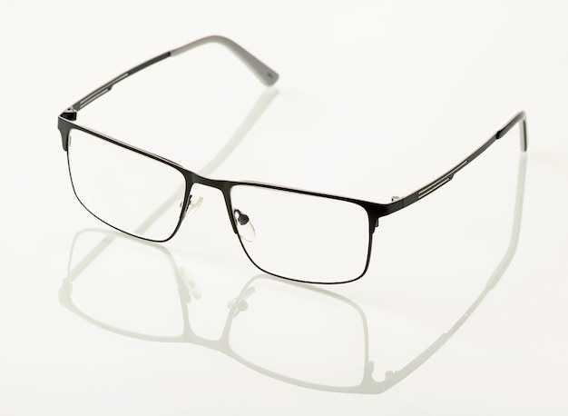 Glasses in a black metal frame are reflected in a white mirror background