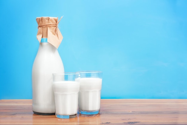 Glasses and bottle with milk on blue