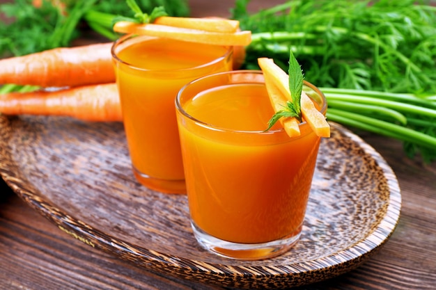 Glasses of carrot juice with vegetables on table close up