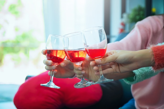 Glasses of champagne close up, celebration, eating and holidays, hands clinking wine glasses, Focus on hands toasting red wine glass