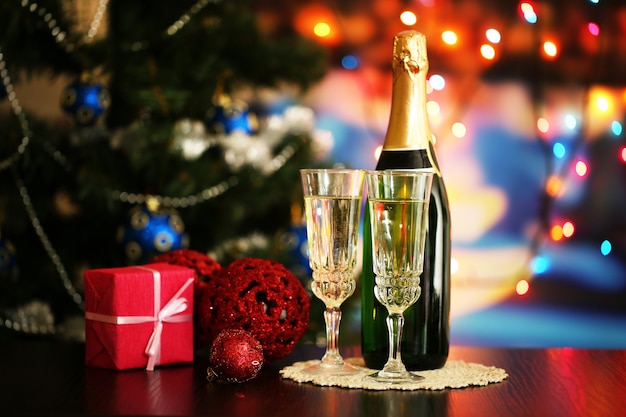 Glasses of champagne and gift on bright background