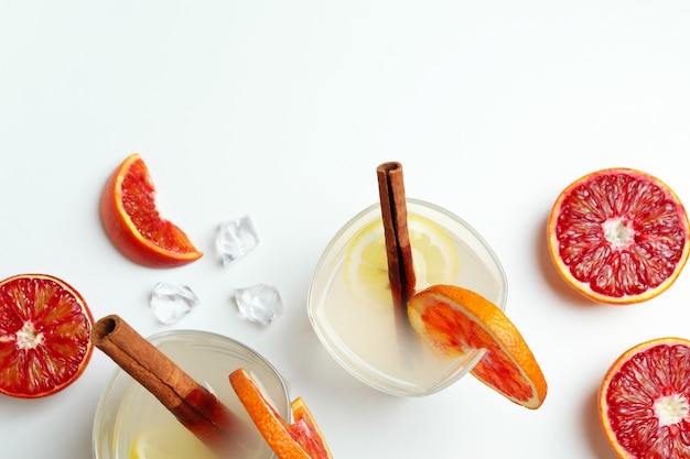 Glasses of cocktail with citrus on white surface