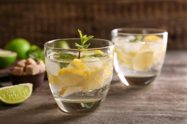 Glasses of cocktail with lemon and mint on wooden table