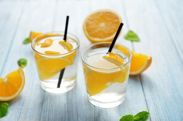 Glasses of delicious cocktails with orange on table