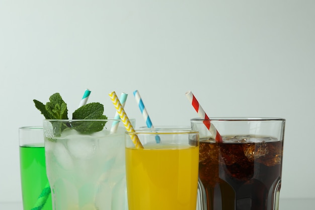 Glasses of different soda on white surface