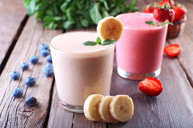 Glasses of fresh cold smoothie with fruit and berries on wooden background