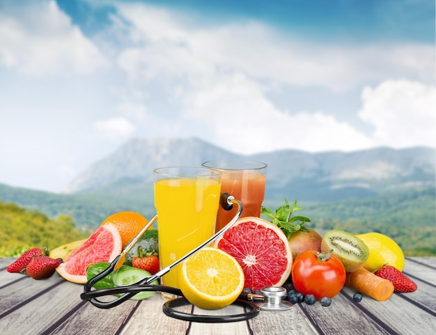 Glasses of fresh juice and fruits with vegetables and measuring tape