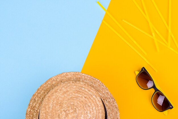 glasses and hat with shells and sea stars on a colored surface