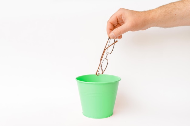 The glasses is thrown into the trash basket for disposal and recyclingWhitebackground