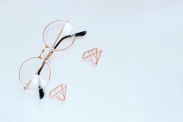 Glasses paper clips in the form of rose gold diamonds on a background on a white background