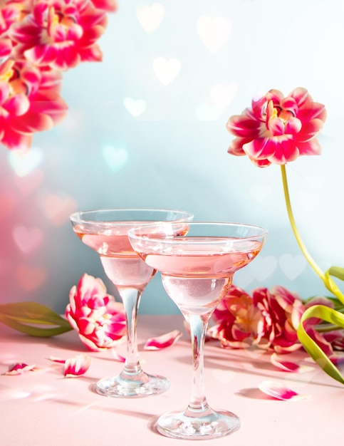 Glasses of pink cocktail with flowers and petals Birthday party or Valentines day romatic couple date concept