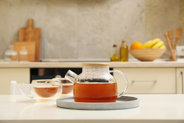 Glasses and pot of tea against kitchen interior