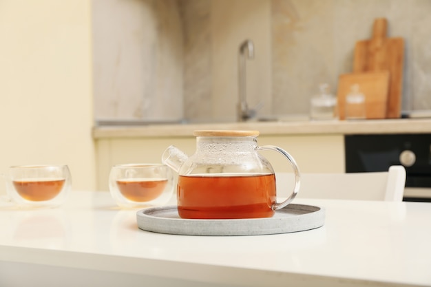 Photo glasses and pot of tea against kitchen interior