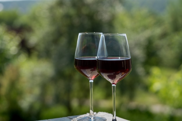 Glasses of red wine over green garden background,outdoor.