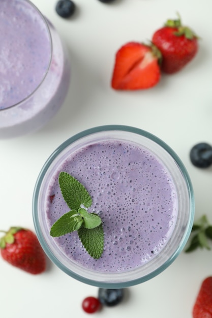 Glasses of smoothie and ingredients on white background