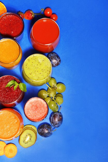 Glasses of tasty fresh juice on blue background