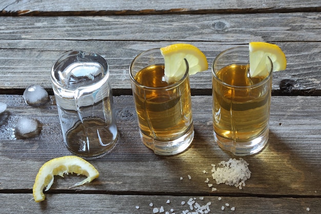 Glasses of tequila with lemon and salt on a wooden table