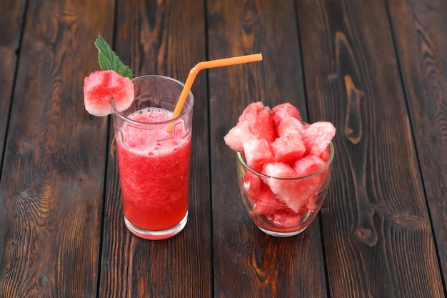 Glasses of watermelon smoothie and heart shapes on wooden table