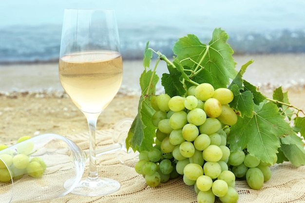 Glasses of wine and fresh grapes on beach