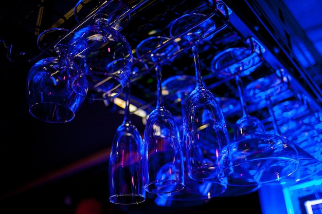 Glasses of wine. Glasses hanging above the bar in the restaurant. blue lights, blue background