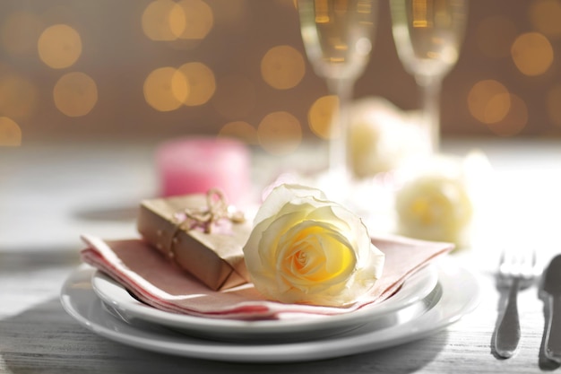 Glasses of wine and white roses, on blurred background