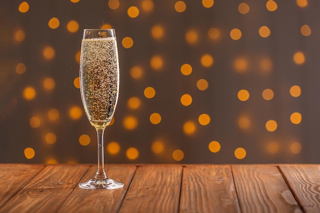 Glasses with champagne on a wooden background against a bokeh background of lights