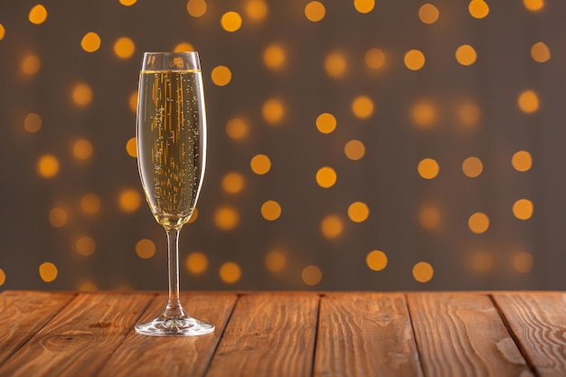 Glasses with champagne on a wooden background against a bokeh background of lights