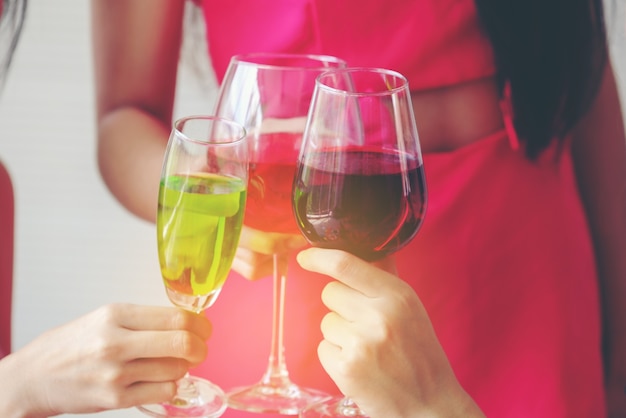 Glasses with cocktails held by happy friends at party