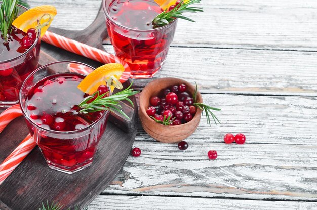 Glasses with cranberry juice Cranberries limes rosemary On a rustic background Top view Free space for your text