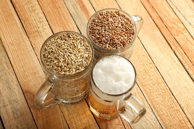 Glasses with fresh beer wheat and barley on wooden background