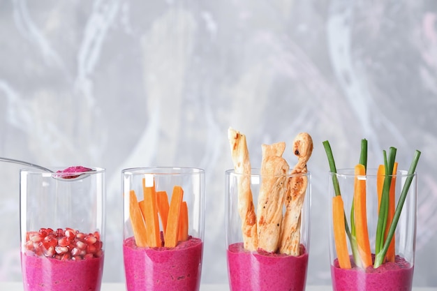 Glasses with fresh beet hummus on light background