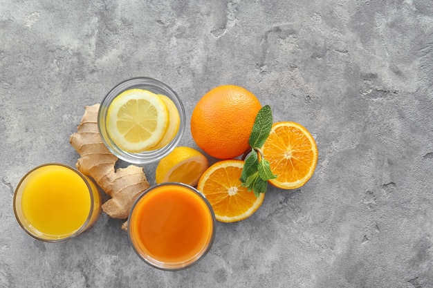 Glasses with juice and citrus fruits on grey background. Healthy food concept