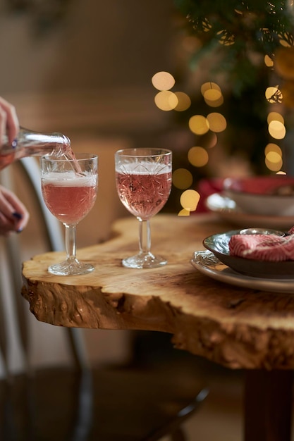 glasses with red champagne stand on a wooden table against the bokeh background