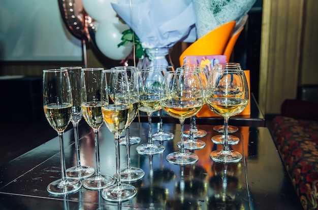 Glasses with a welcome drink on black wooden table, side view close-up.