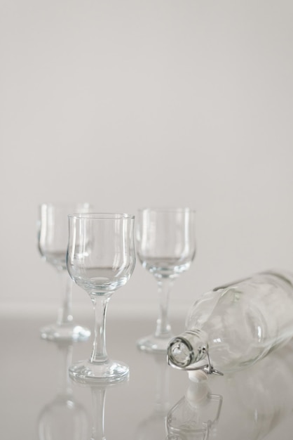 Glassware on glass table. Three wine glasses and empty bottle. Catering concept