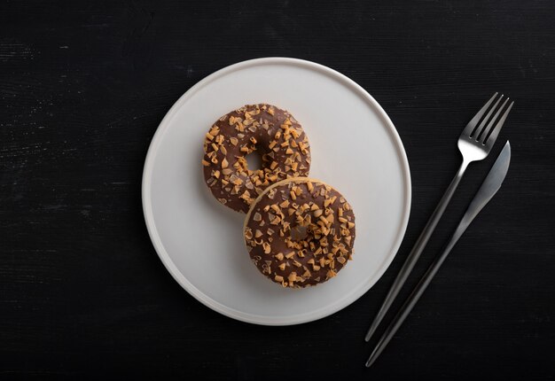 Glazed chocolate donuts on a plate on wooden table