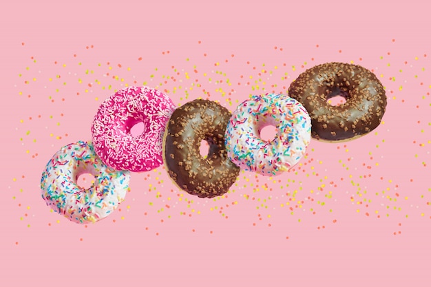 Glazed doughnuts in motion falling on pink with colorful sprinkles