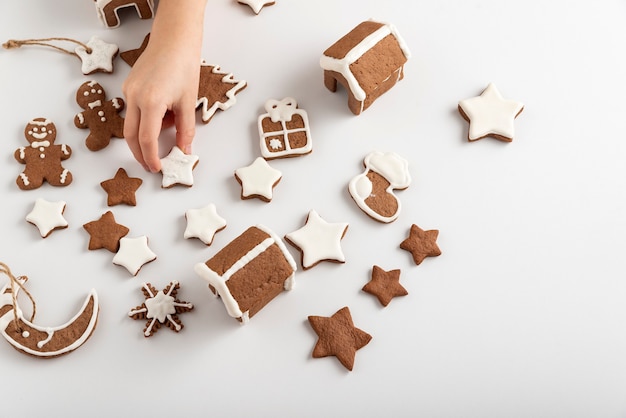 Glazed gingerbread cookies on a white table and a child's hand. Preparing for Christmas. Top view.