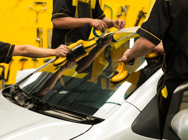 Glazier is repairing  windshield of the car