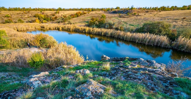 A gleaming beautiful little river among large white stones and green vegetation on the hills in Ukraine