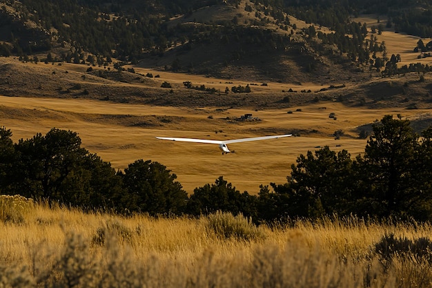 Photo glider soaring over a valley in the golden hour