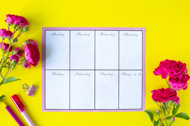 Glider with notes and to-do list on a yellow background with pink stationery and flowers. Business concept. Top view