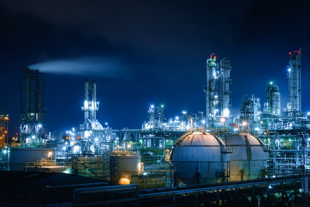 Glitter lighting of petrochemical industrial plant at night with gas storage sphere tanks and smoke stack