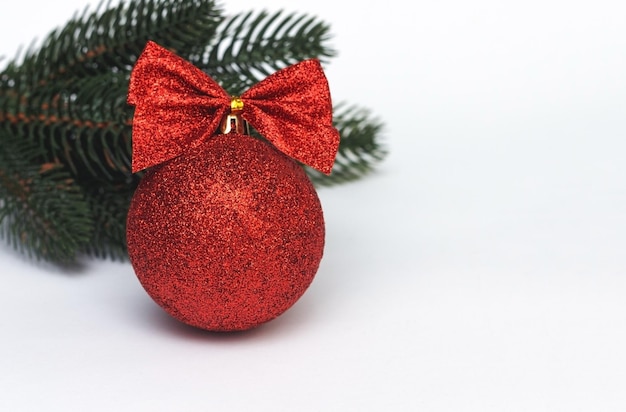 Glitter red christmas ball with ribbon and green branch of fir.