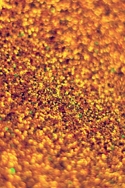 Glitter splash and lens flare on orange gold shiny trendy background. Sequins. Festive background for your projects. Blurred orange festive bokeh lights. Christmas festive time concept on background.