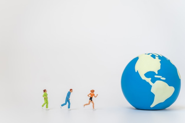 Global sport health concept. Group of runner miniature figure people running to mini world ball