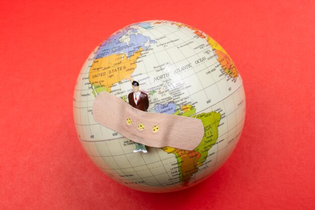 Globe Earth with a man figurine plaster banded aid on