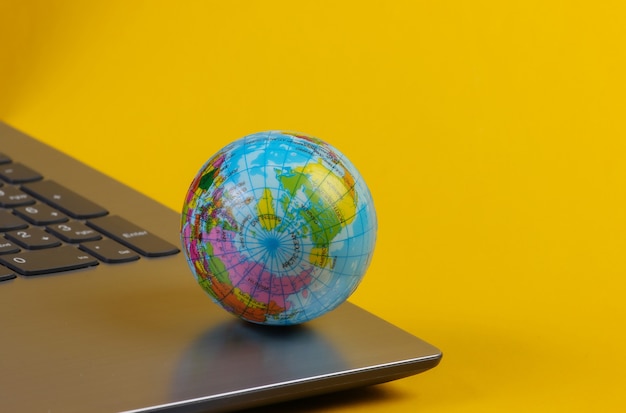 Globe on a laptop keyboard. World Wide Web, online. Yellow  background