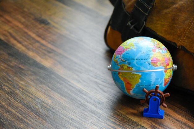 Photo globe showing maps of america and africa with miniature ship steering wheel model for world travel and maritime business concepts on the wooden pattern table